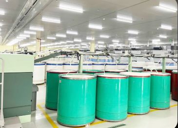 Large green cylindrical containers in a brightly lit industrial setting.