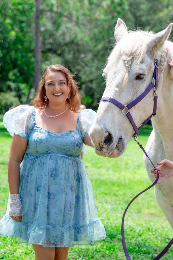 Woman smiles while petting horse during photoshoot