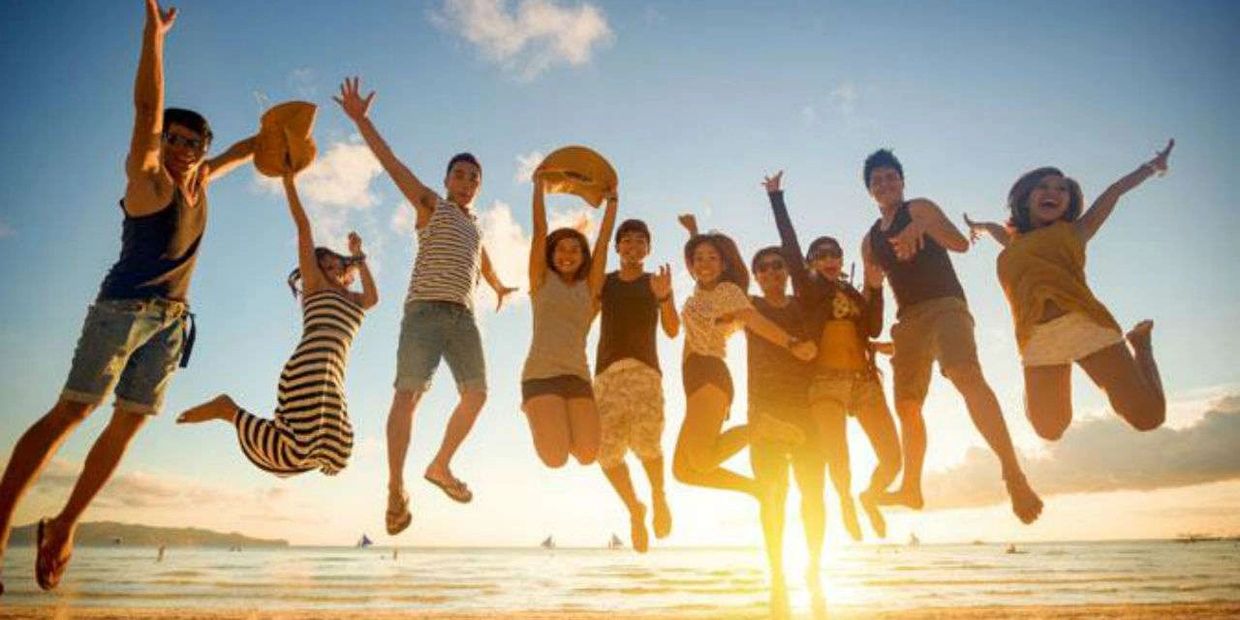 Group of friends joyfully jumping on a beach at sunset.