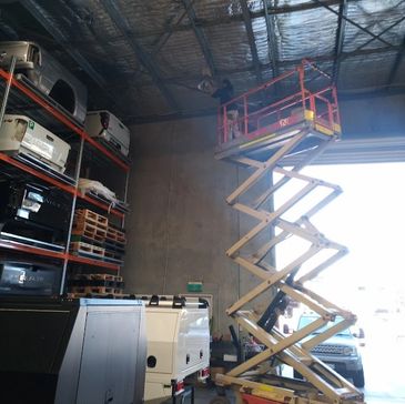 Electrician on scissor lift installing high bay warehouse lighting