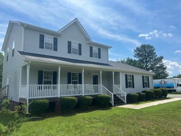 Large two-story white house with blue shutters and porch.