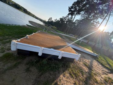 Wooden dock on a lake shore at sunset.