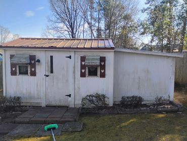 White garden shed with heart-decorated shutters.