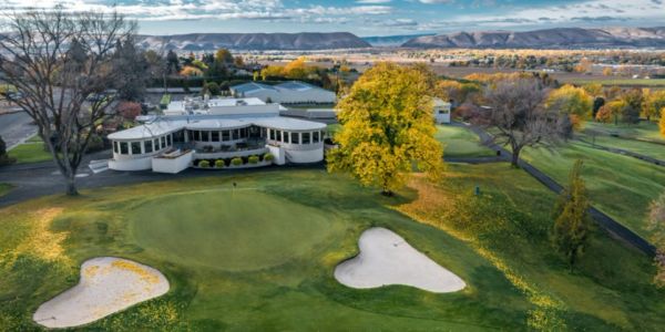 A golf course with a clubhouse surrounded by autumn trees.