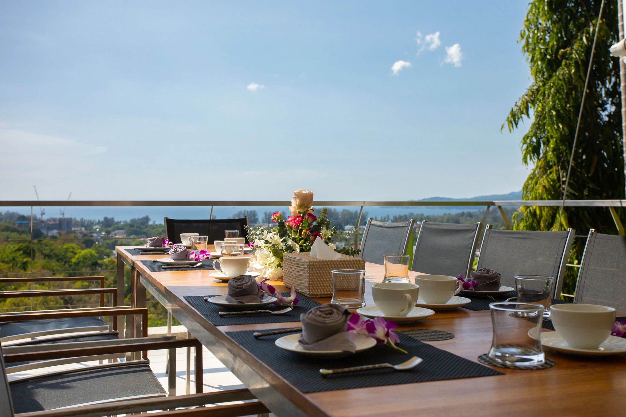 A table set for dinner on a villa terrace overlooking the bay