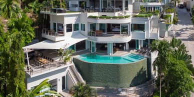 Modern hillside villa with infinity pool and outdoor dining area.