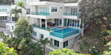 Modern house with a blue-tiled swimming pool surrounded by greenery.