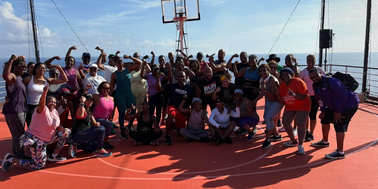 Group of people flexing muscles on an outdoor basketball court by the sea.