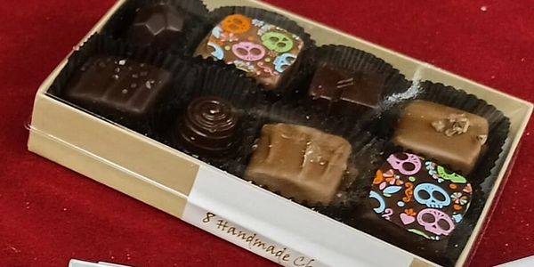Box of assorted handmade chocolates with colorful skull designs.