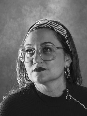 Black and white portrait of a woman with large glasses and a patterned headband.