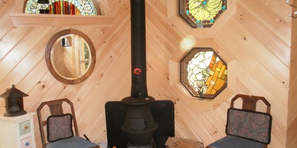 Cozy wood stove with two chairs in a wooden cabin corner.