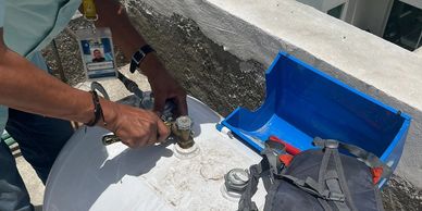 Person using a wrench to work on a water tank valve outdoors.