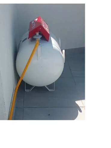 Large white propane tank connected with an orange hose placed outdoors.