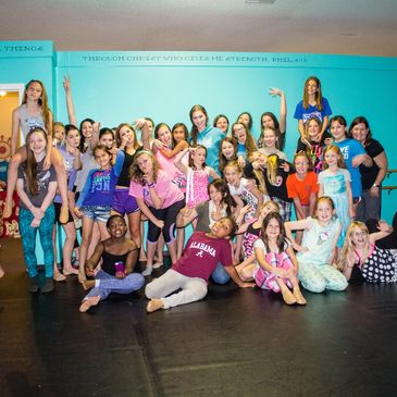 A large group of joyful children posing together in a colorful room.