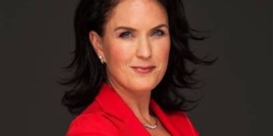Professional woman in a red blazer with dark hair and blue eyes.