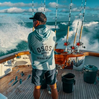 Man fishing on a boat with several fishing rods and fish on the deck.
