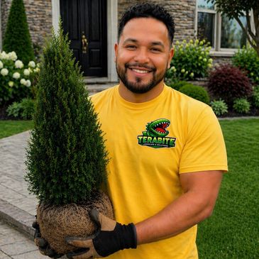 Smiling man holding a small tree with soil, wearing a yellow Terabite shirt.