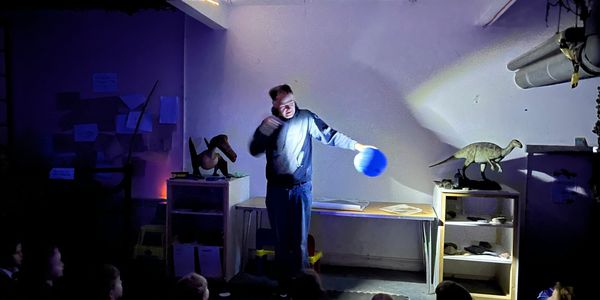 presenter neil carrington talking about light and shadow by shining a torch on the earth