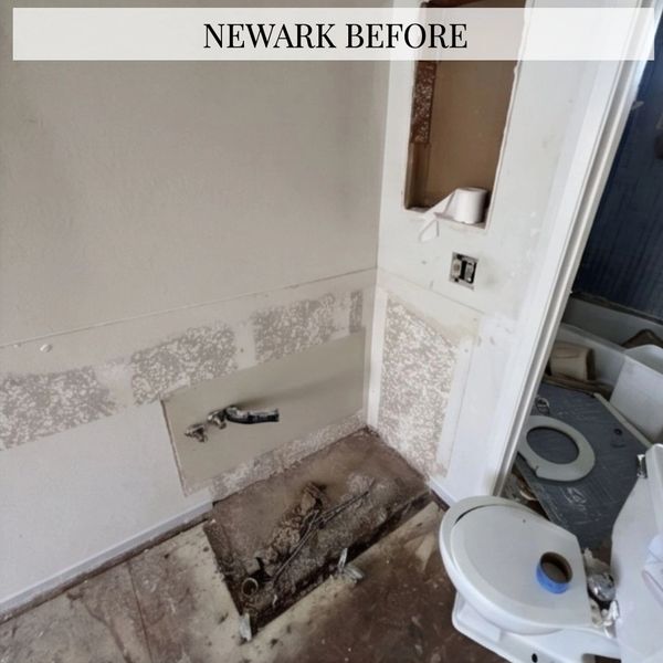 Dilapidated bathroom with missing fixtures and exposed plumbing.
