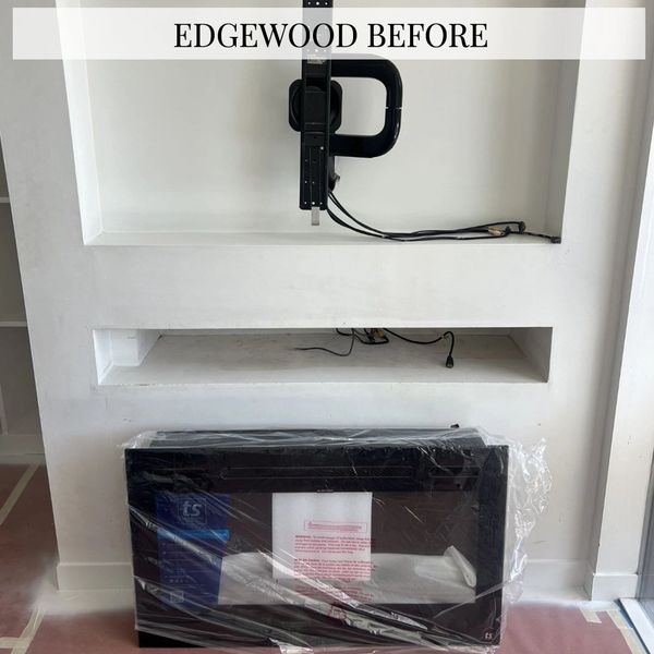 Empty recessed wall space with TV mount and wrapped fireplace below.