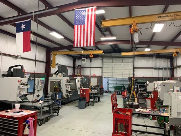 A clean and organized industrial workshop with American and Texas flags.