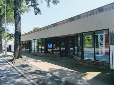 Empty commercial storefront with 'For Rent' sign and 'Now Leasing' banner.