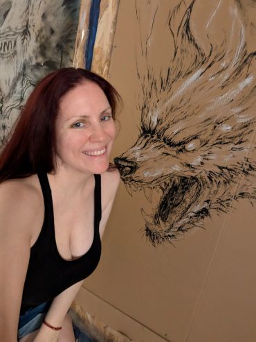 Woman smiling next to a fierce wolf drawing.