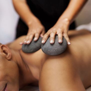 Person receiving a hot stone massage on their back.