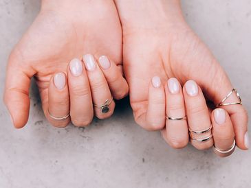 Hands with manicured nails and silver rings on fingers.