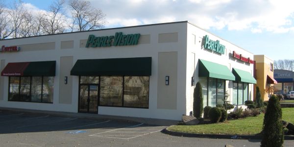 Storefronts with green awnings and parking lot.