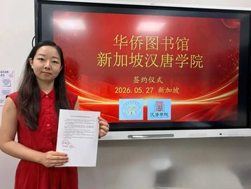 A woman holds a document in front of a screen displaying a signing ceremony announcement in Chinese.