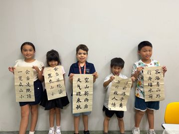Five children proudly display calligraphy scrolls with Chinese characters.