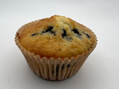 A blueberry muffin in a paper liner on a white background.