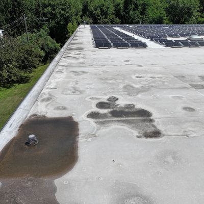 Flat commercial rooftop with visible signs of water pooling around a drain indicates drainage issues