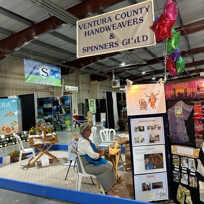 Woman spinning yarn at Ventura County Handweavers &amp; Spinners Guild booth.