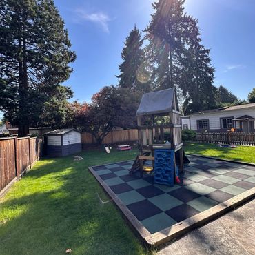 Sunny backyard with a children's playset on a checkered mat.
