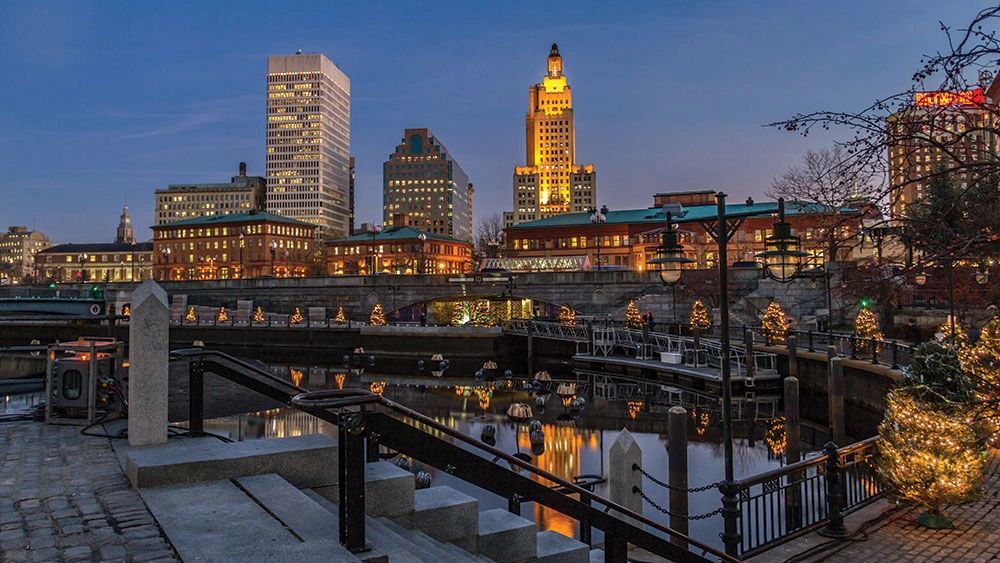 A view of a dock and large buildings with elegant lights