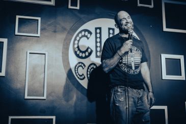 Comedian performing on stage with microphone.