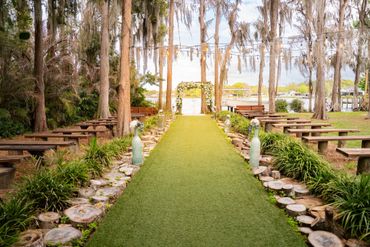 Outdoor wedding aisle decorated with greenery and wooden benches.