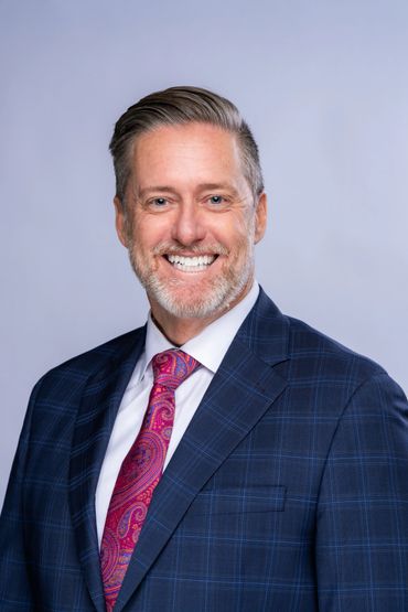 Smiling businessman in a blue checkered suit and colorful tie.
