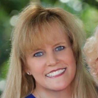 Smiling woman with blonde hair and blue eyes in a blue top.