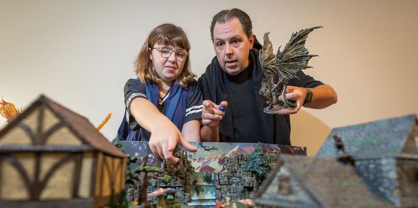 Two people playing tabletop RPG with detailed miniatures.