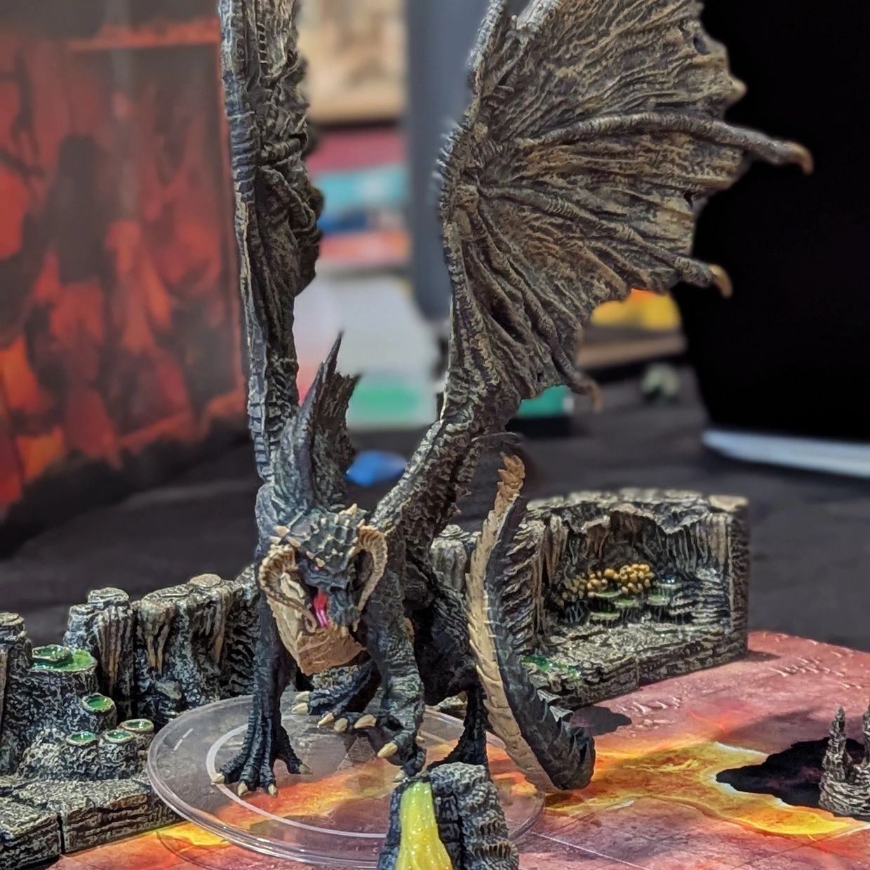 A detailed dragon miniature on a fiery lava game board with a warrior figure.