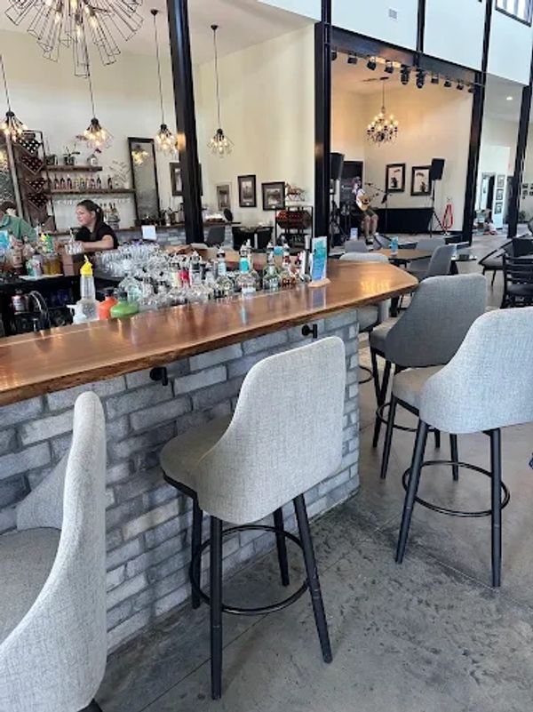 Modern bar area with gray upholstered stools and stylish lighting fixtures.