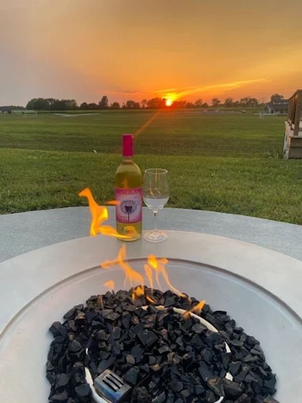 Sunset with wine, glass, and fire pit creating a relaxing outdoor scene.