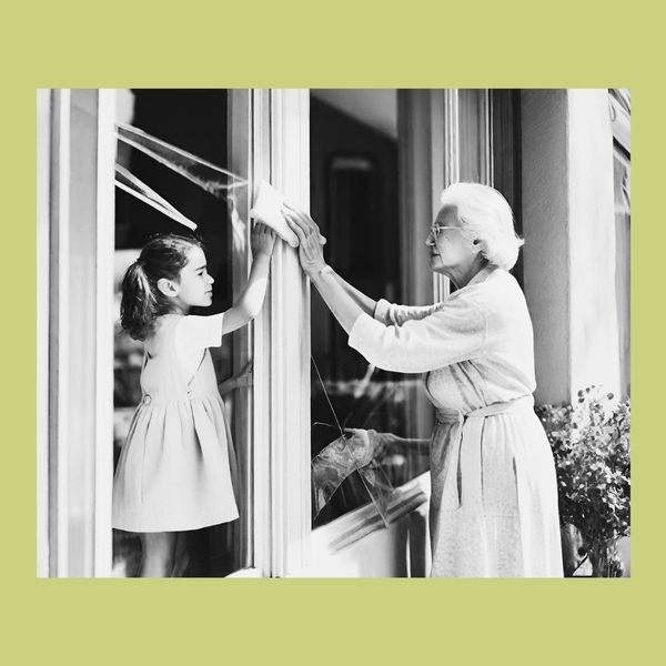 Grandma showing how to clean windows to her granddaughter