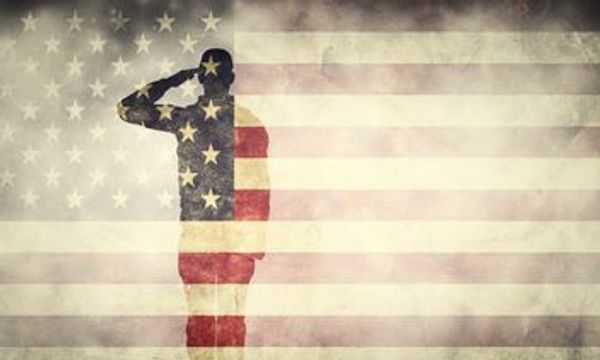 Soldier silhouette saluting superimposed on a faded US flag.