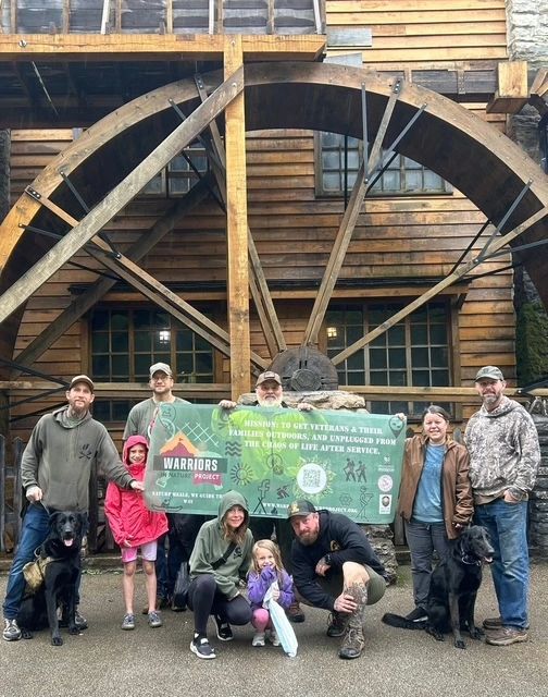 Group photo in front of a large wooden water wheel.