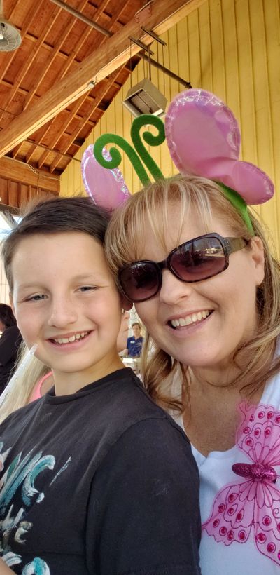 Woman with purple butterfly headband and boy smiling for selfie.