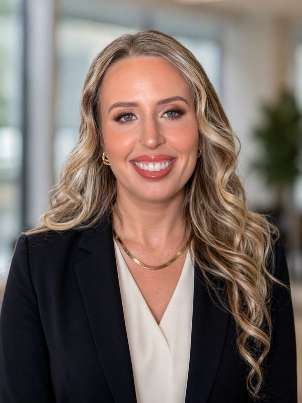 Professional woman with long blonde hair, wearing a black blazer and smiling.